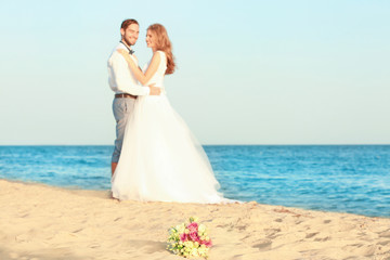 Wall Mural - Beautiful bouquet and happy wedding couple on sea beach