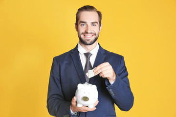 Sticker - Young man with piggy bank on color background