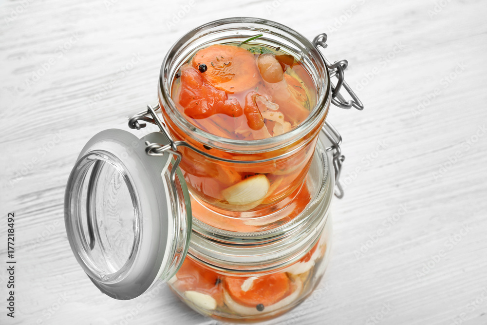 Jars with delicious marinated salmon on table