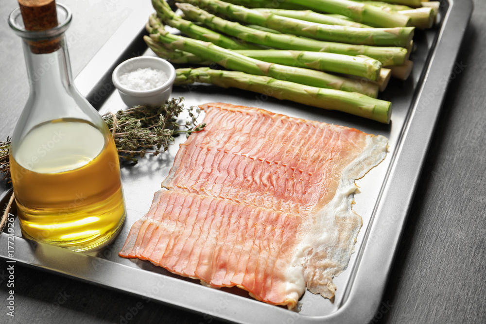 Plate with bacon wrapped asparagus on light background