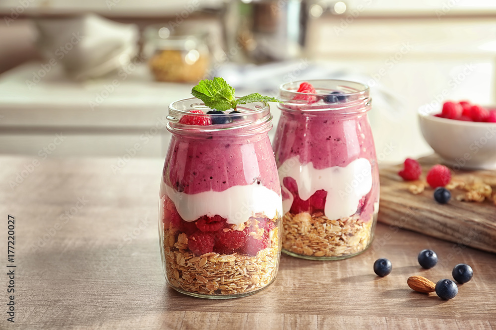 Glass jars with acai smoothie and berries on blurred background