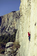© Vitalii Nesterchuk - Young man climbs on a rocky wall in a valley with mountains.