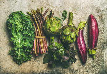 Wall Mural - Flat-lay of green and purple fresh vegetables over concrete background, top view. Local seasonal produce for healthy cooking. Eggplans, green beans, kale, asparagus, artichoke, basil. Clean eating