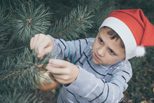 Happy Young Little Boy Decorating Christmas Tree.