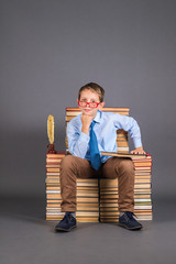 Wall Mural - Education funny concept. A boy student sitting on a throne from books