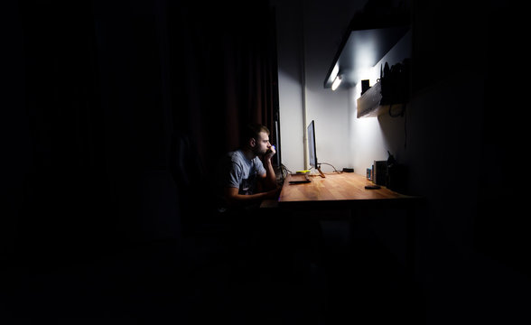 Fototapete - man works, resting at night at the computer in the room at home,  in the dark