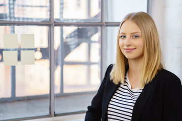 Canvas Print - junge frau steht lächend am fenster im büro