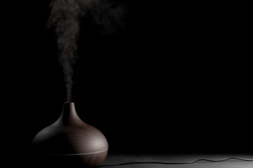 electric aromatherapy device. electronic diffuser gadget in use against black background.