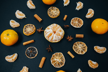 Wall Mural - Christmas mandala with mandarines, cinnamon, anise stars, dried orange slices a black background.