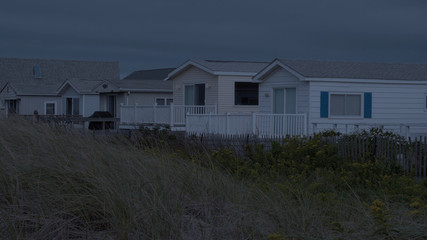 Generic ocean front beach house condo view night time exterior. Luxury real estate along sand dunes for summer home vacation location