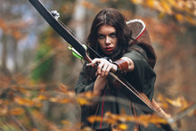 Portrait Of A Beautiful Brunette Woman Taking Aim With Bow And Arrow