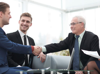 Partners concluding deal and shaking hands in the presence of team members