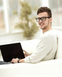 © ASDF - modern young man working on laptop sitting in the living room.