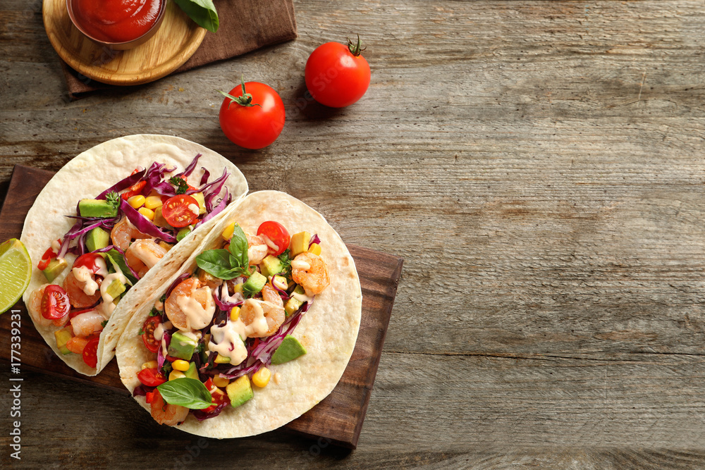 Board with delicious shrimp tacos on wooden table