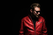 © _robbie_ - Cool man in a red leather jacket with sunglasses standing against a black background.