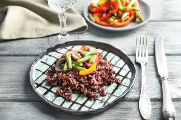 Canvas Print - Plate with red rice and vegetables on wooden table