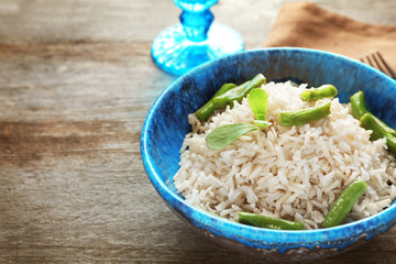 Canvas Print - Bowl with brown rice and green beans on wooden table