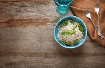 Canvas Print - Bowl with brown rice and green beans on wooden table