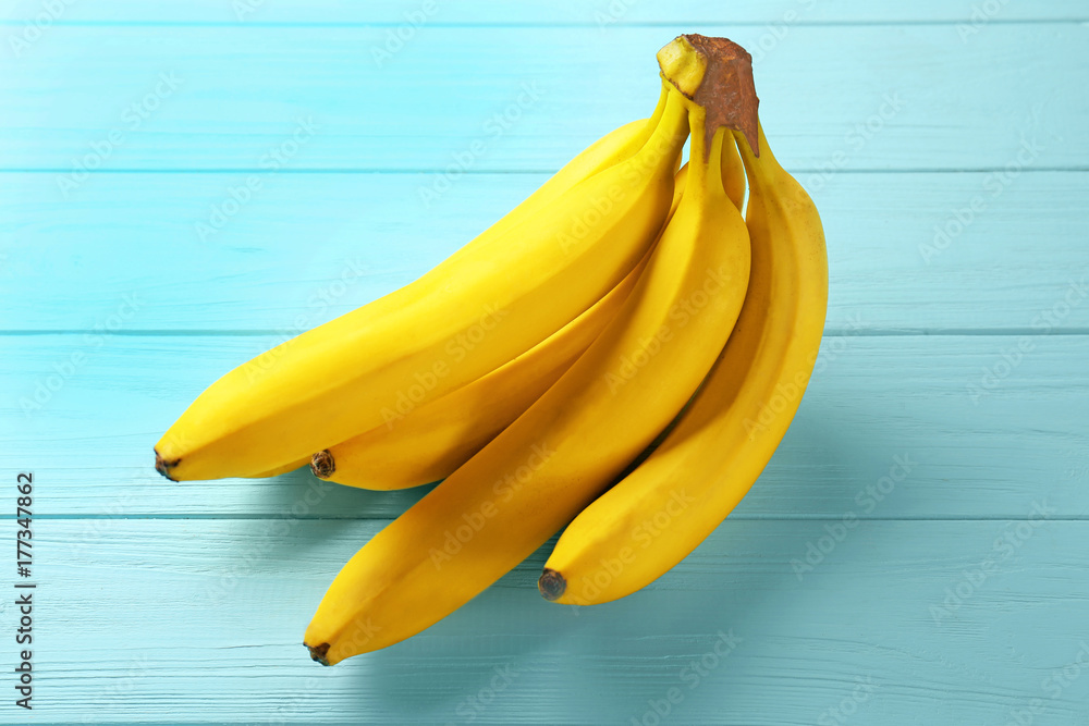 Ripe bananas on color wooden background