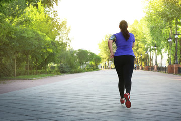 Overweight young woman jogging in park. Weight loss concept