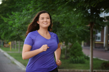 Wall Mural - Overweight young woman jogging in the street. Weight loss concept