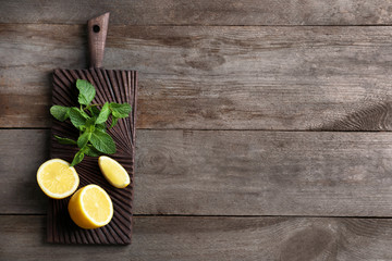 Wall Mural - Cutting board with mint and lemon on wooden background