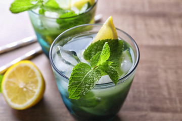 Wall Mural - Glass of cocktail with lemon and mint on wooden background