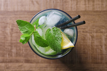 Glass of cocktail with lemon and mint on wooden background