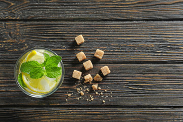 Wall Mural - Glass of cocktail with mint and lemon on wooden background