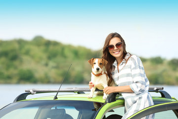 Canvas Print - Beautiful young woman with cute dog near car on river shore