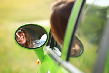 Wall Mural - Young woman looking in car side mirror