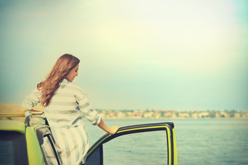 Wall Mural - Beautiful young woman near car on river shore