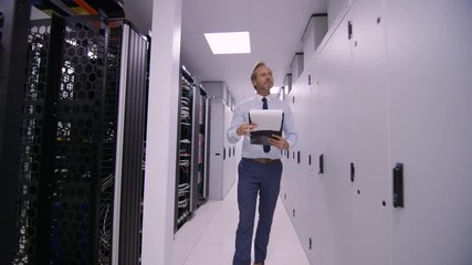 Data administrator walking between rows of server racks and checking the machines.