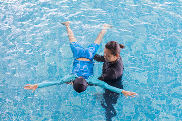 Wall Mural - Girl learning to swim with coach at the leisure center