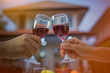 © I'm Thongchai - Man hand and woman hand holding a glass of red wine to celebrate Christmas and New Year. The back of the house is a bokeh of light. In the evening when entering the winter.