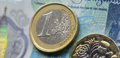 Wall Mural - One euro and one pound coin with a five pound note background - European currency concept in a web banner format. 