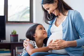 daughter touching the belly of her pregnant mother