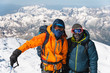 © yanik88 - Portrait climber in a down jacket and harness he is standing next to his friend on the way to the top of a snow-capped mountain