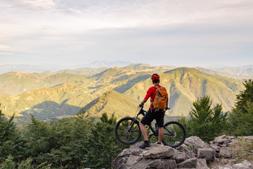 Mountain biker looking at view on bike trail in autumn mountains.