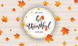 Thanksgiving. Be Thankful calligraphy and falling autumn leaves on wooden background. Thanksgiving Day banner