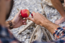 Man's Hand Cutting Apple At Camp Fire
