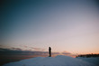 © Daring Wanderer/Stocksy - Silhouette of man standing on snowy hill alone at sunset