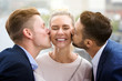 © wernerimages - two young men kissing woman on her cheeks