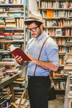 Stylish Hipster Man Reading In A Bookshop