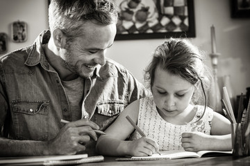 Wall Mural - A father helps his little daughter to do her homework for the school.