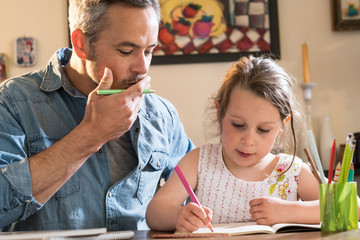 Wall Mural - A father helps his little daughter to do her homework for the school.