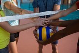 Coach and female players holding volleyball