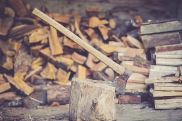 Wall Mural - An axe stuck in piece of wood, ready for cutting a log / timber, pile of wood on a background