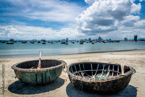 Photographie Old fishing boats next to modern skyline in Da Nang