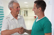 © dream@do - Smiling male doctor giving handshake to senior male patient. Health care concept